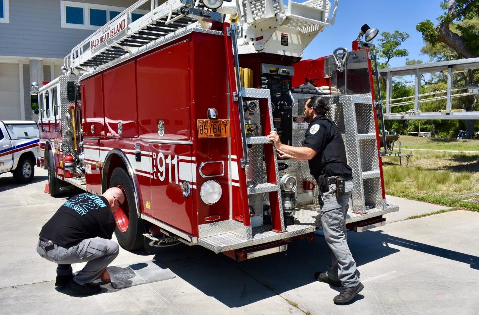 Bald Head Island public safety officers Brandon Fuller, left, and Chip Sudderth work on the department's ladder truck on Wednesday, April 27, 2022.