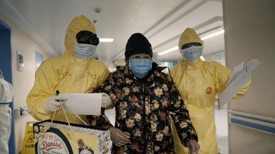 An elderly woman with COVID-19, center, is escorted by two nurses after being admitted to a hospital in Wuhan, China in a scene from the documentary "76 Days." The film, shot in four Wuhan hospitals, captures a local horror before it became a global nightmare. Given the constraints at the time on footage and information from Wuhan, it's a rare window into the infancy of the pandemic. (MTV Documentary Films via AP)