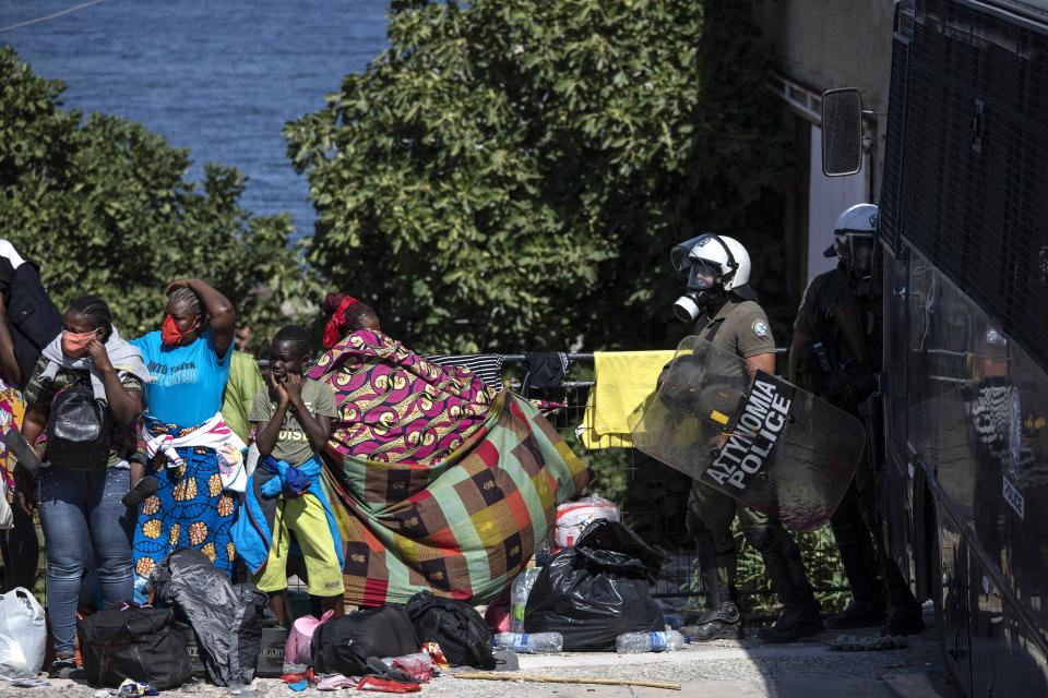 Migrants take part in a rally as riot police block the road near Mytilene town, on the northeastern island of Lesbos, Greece, Friday, Sept. 11, 2020. Thousands of protesting refugees and migrants left homeless on the Greek island of Lesbos after fires destroyed the notoriously overcrowded Moria camp have gathered on a road leading to the island's main town, demanding to be allowed to leave. (AP Photo/Petros Giannakouris)