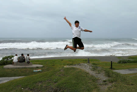 A man jumps as his father takes a photo in front of the coast as Typhoon Nepartak approaches in Yilan, Taiwan July 7, 2016. REUTERS/Tyrone Siu