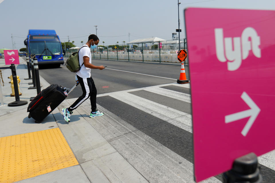 A traveler arriving at Los Angeles International Airport looks for ground transportation and walks past a sign for ride-sharing company Lyft in Los Angeles, August 20, 2020. REUTERS/Mike Blake