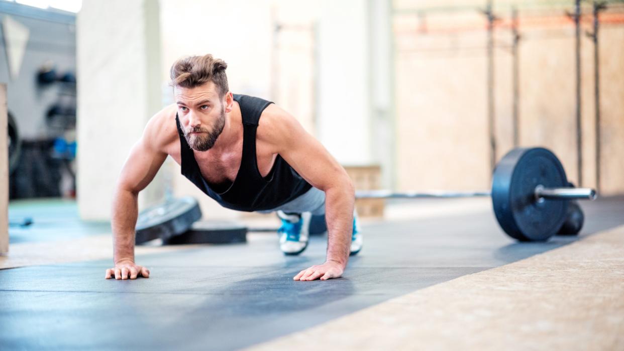  Man performing push-ups during workout in a gym studio . 