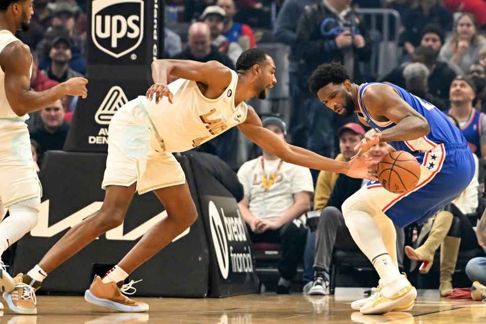 Cleveland Cavaliers forward Evan Mobley, left, knocks the ball away from Philadelphia 76ers center Joel Embiid during the first half of an NBA basketball game, Wednesday, Nov. 30, 2022, in Cleveland. (AP Photo/Nick Cammett)