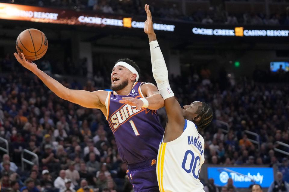 Phoenix Suns guard Devin Booker (1) is fouled by Golden State Warriors forward Jonathan Kuminga (00) during the first half of an NBA basketball game in San Francisco, Tuesday, Oct. 24, 2023. (AP Photo/Jeff Chiu)