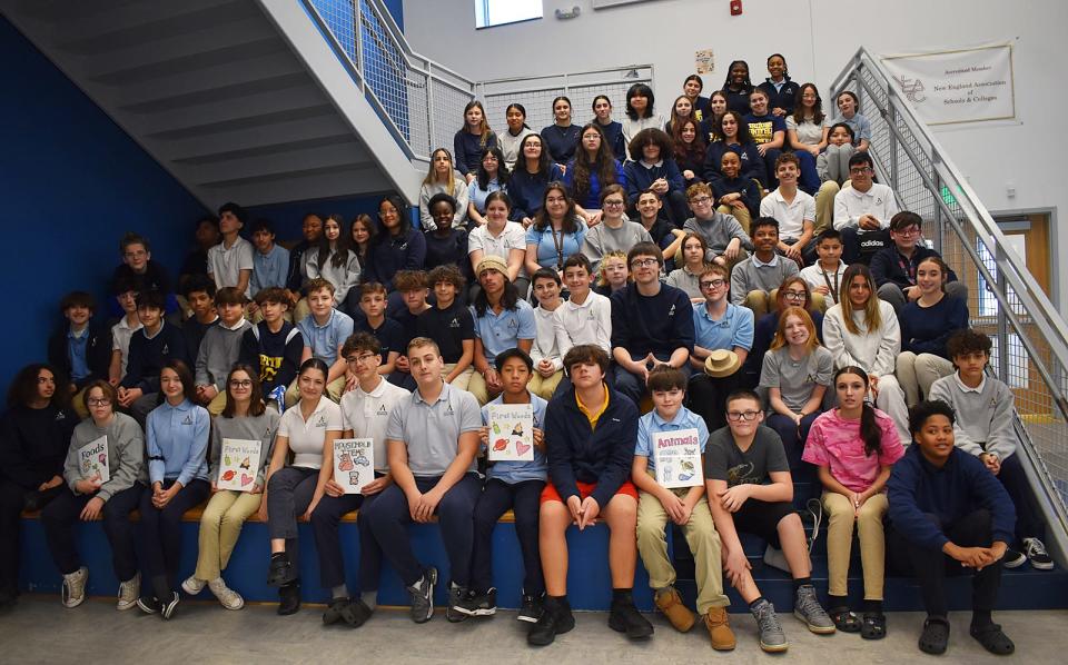 Atlantis Charter School eighth-graders hold copies of picture books they wrote and illustrated, to help teach English to Haitian migrant children living in the Fall River area, on Wednesday, Dec. 20.