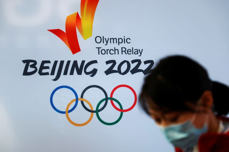 A woman stands in front of the logo of the Beijing 2022 Winter Olympics before the Olympics flame exhibition tour at Beijing University of Posts and Telecommunications, China