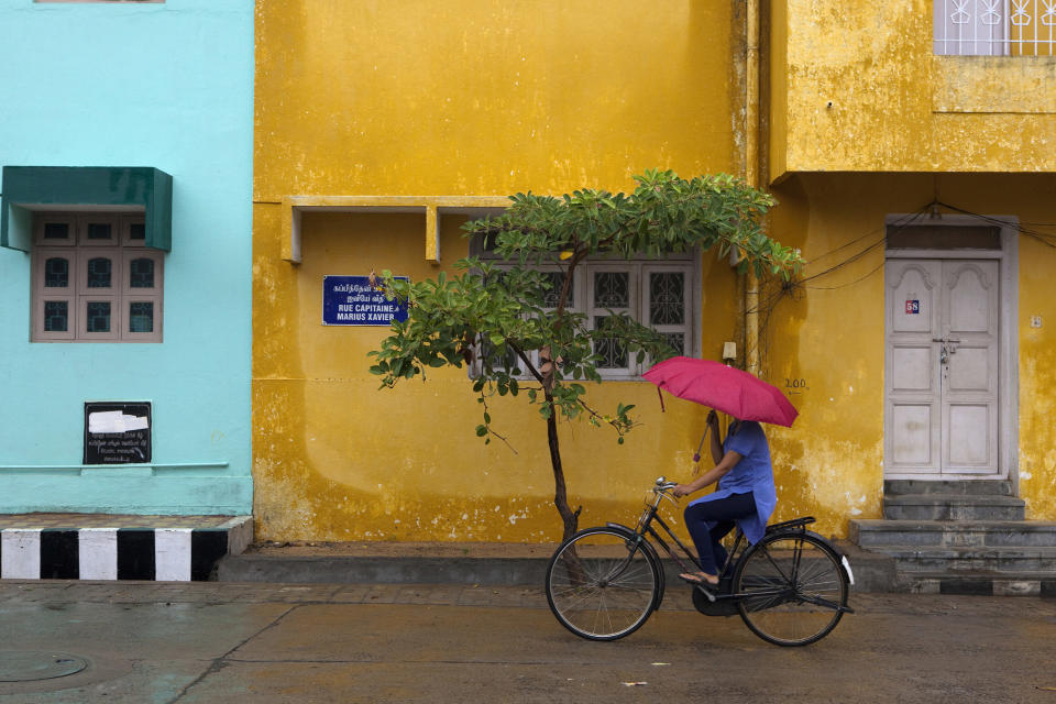 Woman cycling in Pondicherry street with umbrella.