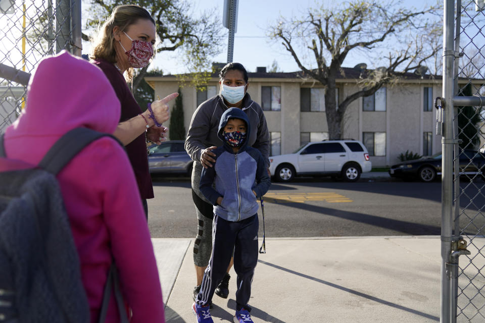 Assistant Principal Janette Van Gelderen, left, welcomes students at Newhall Elementary School Thursday, Feb. 25, 2021, in Santa Clarita, Calif. Elementary school students returned to school this week in the Newhall School District. (AP Photo/Marcio Jose Sanchez)