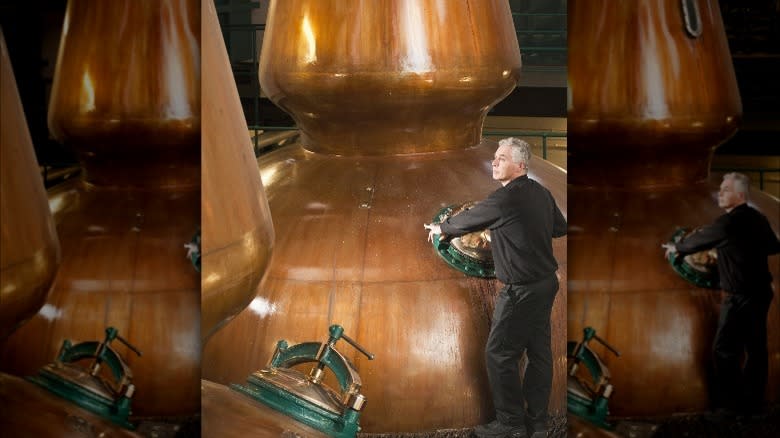 A man standing next to a copper alembic pot still