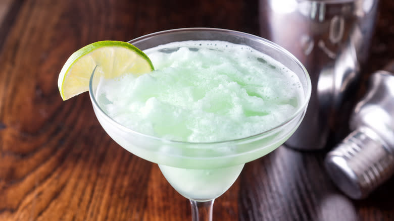 cocktail glass filled with green slush and lime wedge