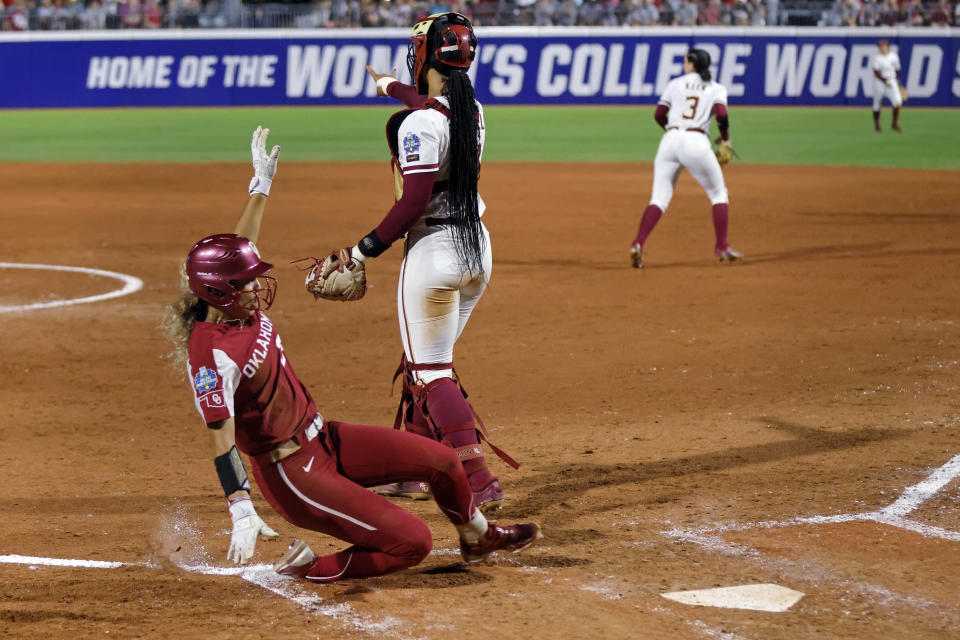 Oklahoma's Jayda Coleman, left, slides home to score past Florida State catcher Michaela Edenfield during the fifth inning of the first game of the NCAA Women's College World Series softball championship series Wednesday, June 7, 2023, in Oklahoma City. (AP Photo/Nate Billings)