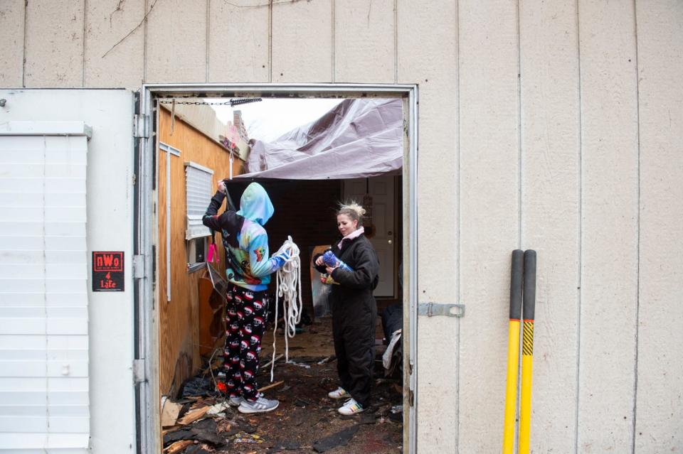 Friends help hang a tarp on Beverly Jordan’s home on Friday, Jan. 13, 2023, the day after a tornado damaged homes along County Road 68 in Marbury, Ala.