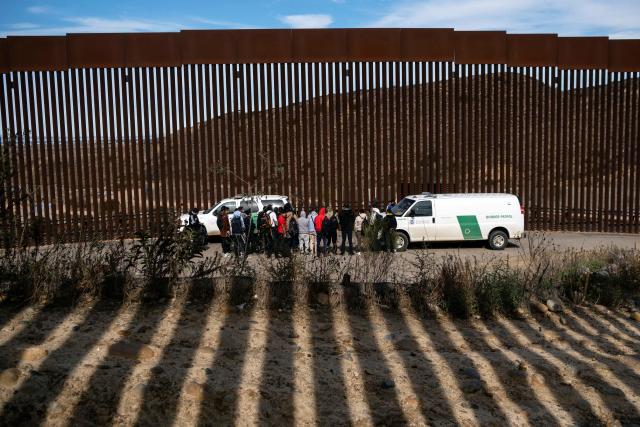 Border patrol agents talk to a group of migrants, mostly from African countries, before processing them after they crossed the US-Mexico border, taken from Tijuana, Baja California state, Mexico, on November 11, 2022. / Credit: GUILLERMO ARIAS/AFP via Getty Images