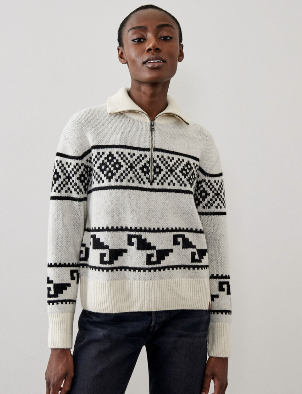 model in dark jeans and white and grey Roots Fair Isle Sweater Stein (Photo via Roots)