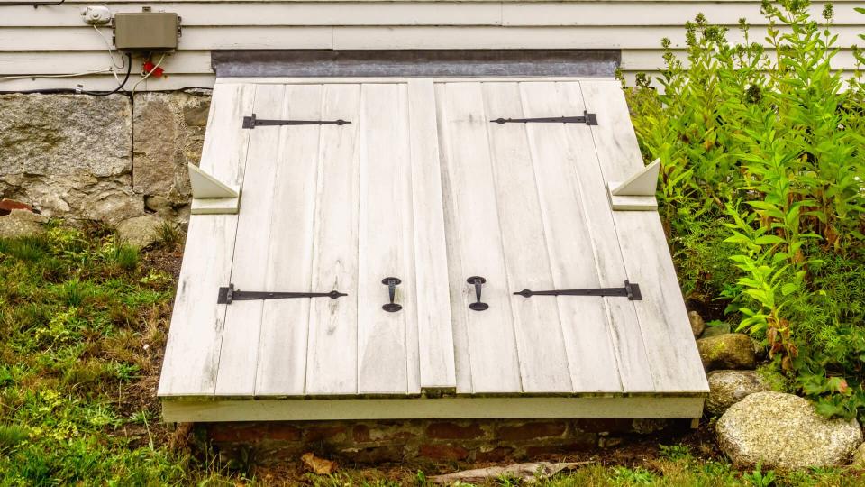 White wooden doors to a storm cellar by stone foundations of an old house in Maine, USA, for themes of stormy weather and safety, readiness, protection - Image.