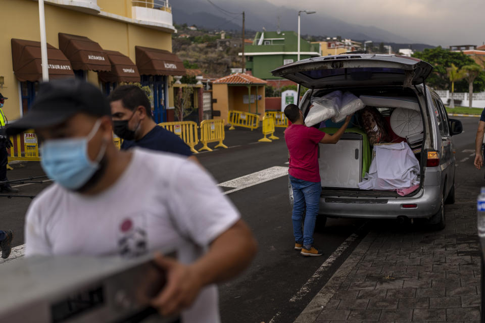 Residents remove their belongings from their houses as lava from a volcano eruption flows, as they are evacuated from their village in Los Llanos, on the island of La Palma in the Canaries, Spain, Wednesday, Sept. 22, 2021. A volcano on a small Spanish island in the Atlantic Ocean erupted on Sunday, forcing the evacuation of thousands of people. Experts say the volcanic eruption and its aftermath on a Spanish island could last for up to 84 days. The Canary Island Volcanology Institute said Wednesday it based its calculation on the length of previous eruptions on the archipelago. (AP Photo/Emilio Morenatti)