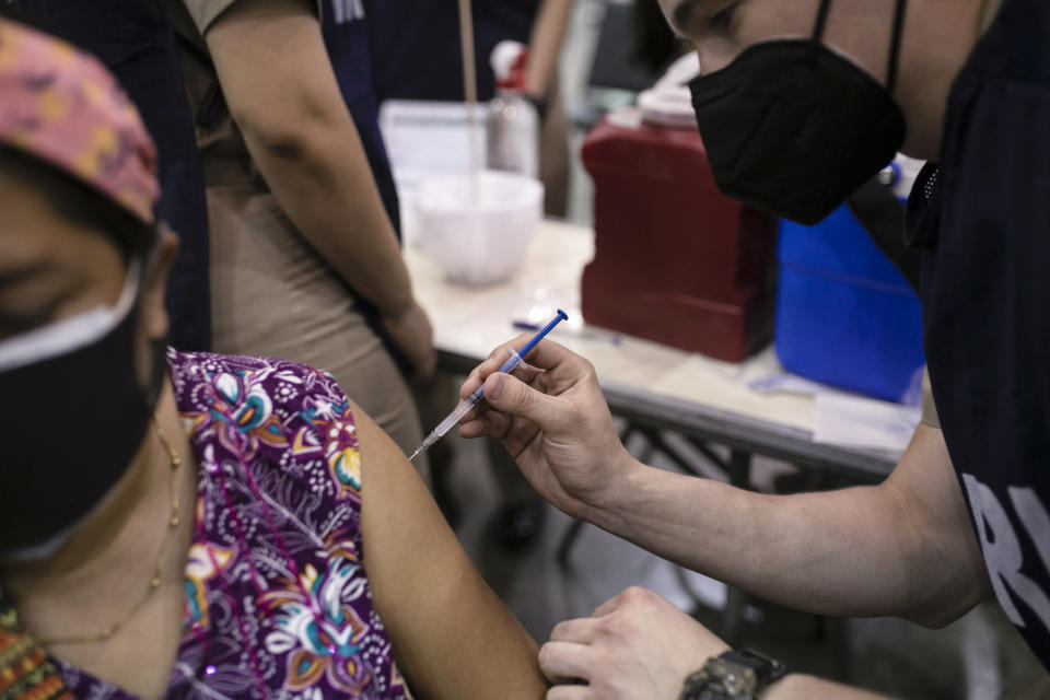 A Navy health worker inoculates a woman with the single-dose CanSino COVID-19 vaccine, during a vaccination drive for education workers at the World Trade Center in Boca del Rio, Veracruz state, Mexico, Tuesday, April 20, 2021. The Mexican government began giving teachers in five other states the single-dose CanSino COVID-19 vaccine to speed up their return to the classroom before the end of the school year in July. (AP Photo/Felix Marquez)