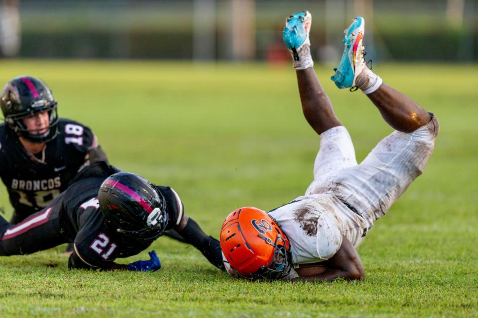 Benjamin's Chauncey Bowens gets trips up by Palm Beach Central's Damon Allen, (21) and Mario Vitola, (18) during their game in Wellington, Florida on October 6, 2023.