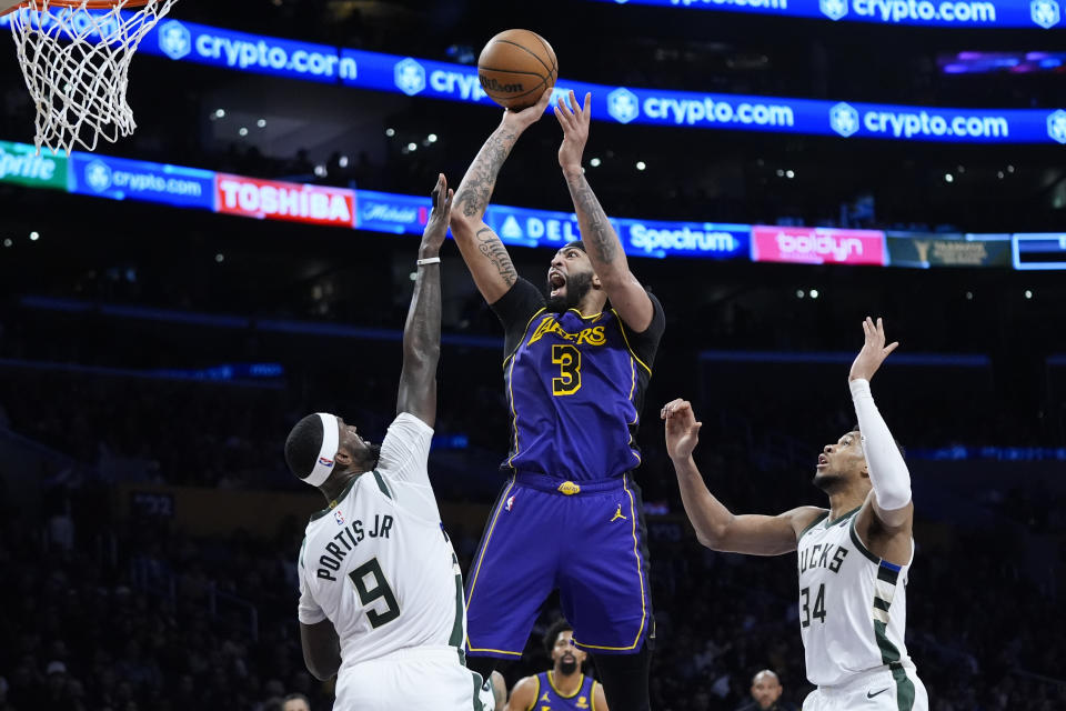 Los Angeles Lakers forward Anthony Davis (3) shoots as Milwaukee Bucks forwards Giannis Antetokounmpo (34) and Bobby Portis (9) watch during the first half of an NBA basketball game Friday, March 8, 2024, in Los Angeles. (AP Photo/Jae C. Hong)