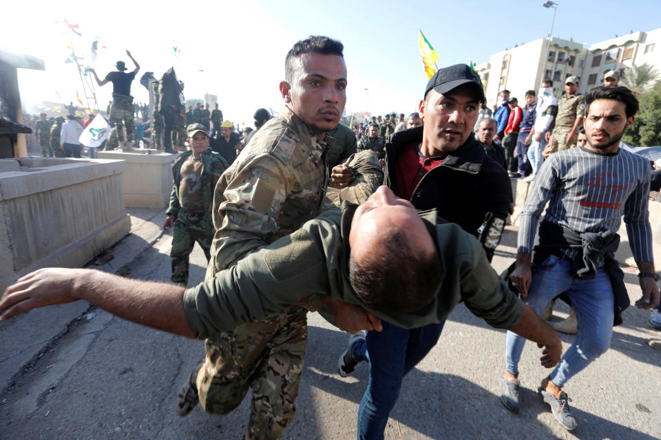 A wounded member of Hashd al-Shaabi (paramilitary forces) gets help during a protest to condemn air strikes on their bases, outside the main gate of the U.S. Embassy in Baghdad, Iraq December 31, 2019. (Photo: Khalid al-Mousily/Reuters)