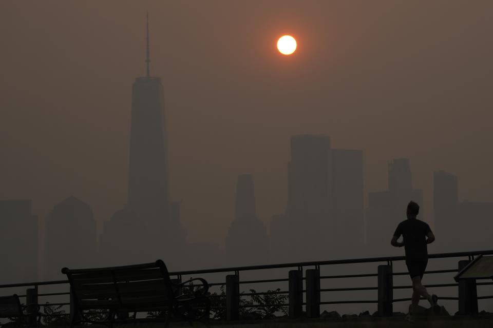 FILE - A man runs in front of the sun rising over the lower Manhattan skyline in Jersey City, N.J., June 8, 2023. Thick, smoky air from Canadian wildfires made for days of misery in New York City and across the U.S. Northeast this week. But for much of the rest of the world, breathing dangerously polluted air is an inescapable fact of life — and death. (AP Photo/Seth Wenig, File)