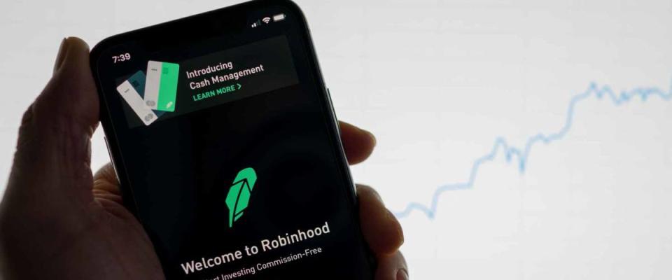 Robinhood app on phone with white financial stock chart with price rising upward positive in background