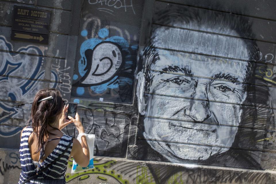 A woman takes a picture of a mural depicting late actor Robin Williams in Belgrade, August 13, 2014. The mural was drawn on a building in downtown Belgrade by an unknown artist on Tuesday. Oscar-winning actor and groundbreaking comedian Williams hanged himself with a belt in his Northern California home after he had sought treatment for depression, a coroner said on Tuesday, based on preliminary findings. REUTERS/Marko Djurica (SERBIA - Tags: ENTERTAINMENT OBITUARY)