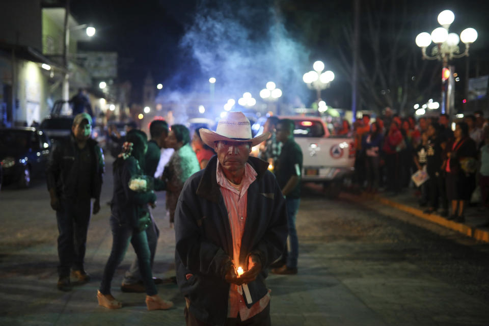 A man carries a candle as mourners gather to greet the hearse bringing the body of Maricela Vallejo, the slain 27-year-old mayor of Mixtla de Altamirano, to her aunt's house for her wake, in Zongolica, Veracruz state, Mexico, Thursday, April 25, 2019. Vallejo, her husband, and a driver were assassinated Thursday by multiple gunmen as they drove along a highway. (AP Photo/Felix Marquez)