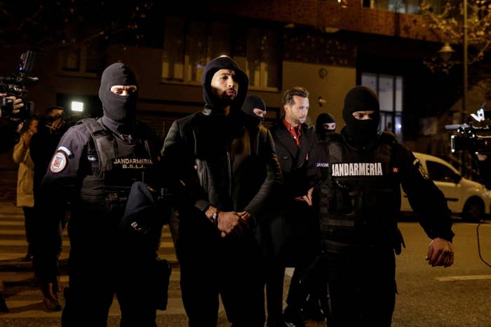 Andrew Tate and Tristan Tate are escorted by police officers outside the Bucharest headquarters of the Directorate for Investigating Organized Crime and Terrorism (DIICOT) after being detained for 24 hours.