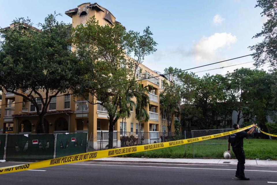 A city of Miami building department worker lifts a caution tape to allow department cars to pass through before the demolition of Temple Court Apartments, 431 NW Third St., Tuesday, June 18, 2024 in Miami, Fla.