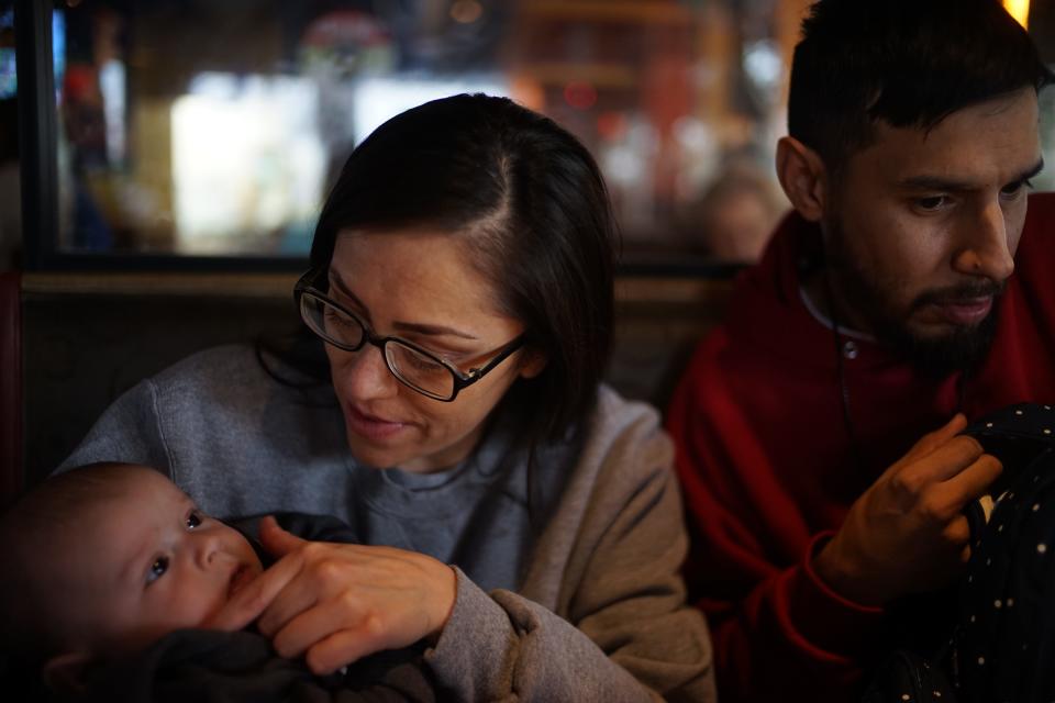 A woman with a baby next to a man in a restaurant booth.