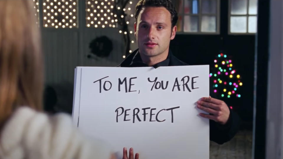 Andrew Lincoln stands with his cue cards in front of Keira Knightley in Love Actually.