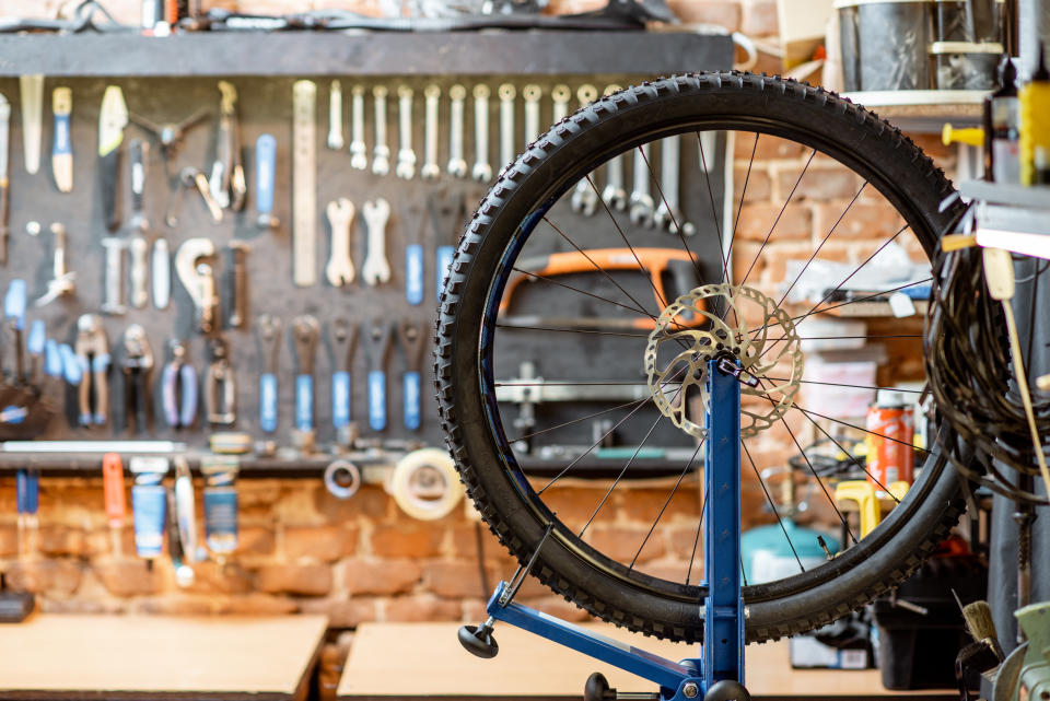 Bicycle workshop with wheel during the aligning process and working tools on the background