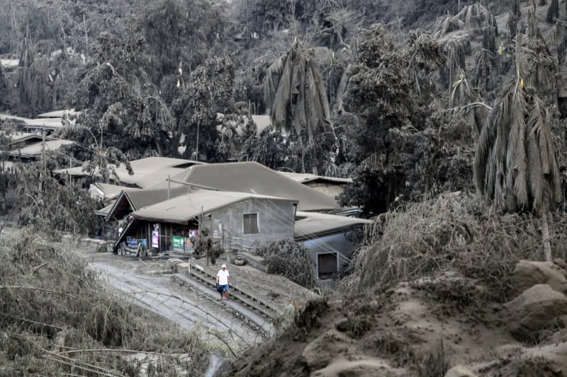 A man walks on a road covered with ashes from the erupting Taal Volcano in Talisay