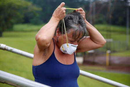 Laura Rillamas, of Orchidland, puts on a dust mask to protect herself from volcanic emissions in Keaau during ongoing eruptions of the Kilauea Volcano in Hawaii, U.S., May 17, 2018. REUTERS/Terray Sylvester