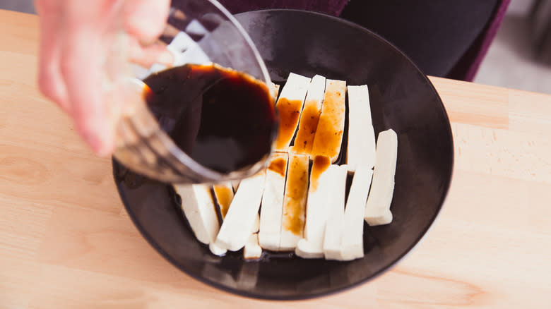 Pouring soy sauce over tofu