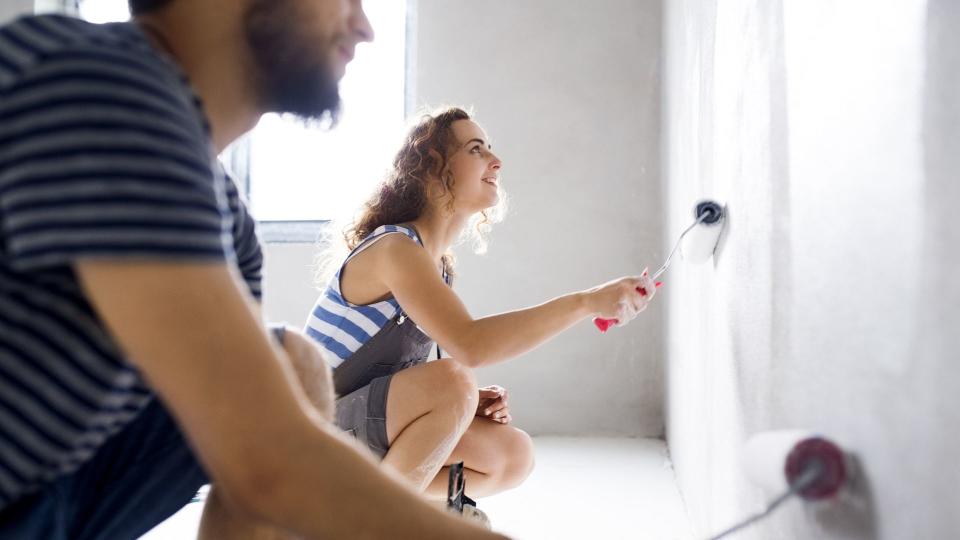 Young couple painting walls in their new house.