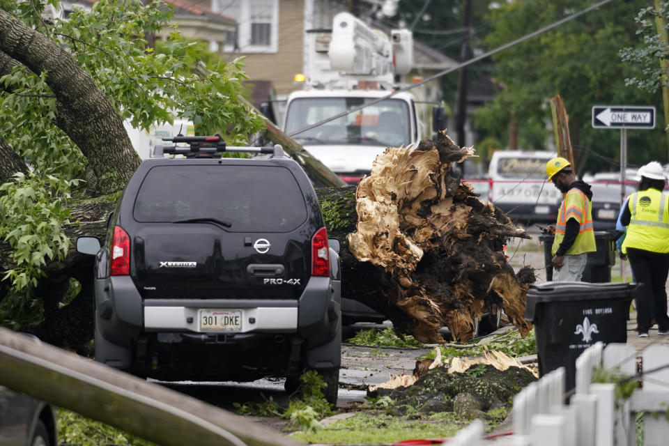 A utility worker stands near an uprooted tree from a possible tornado after heavy storms moved through the area Tuesday night, in the Uptown section of New Orleans, Wednesday, May 12, 2021. (AP Photo/Gerald Herbert)