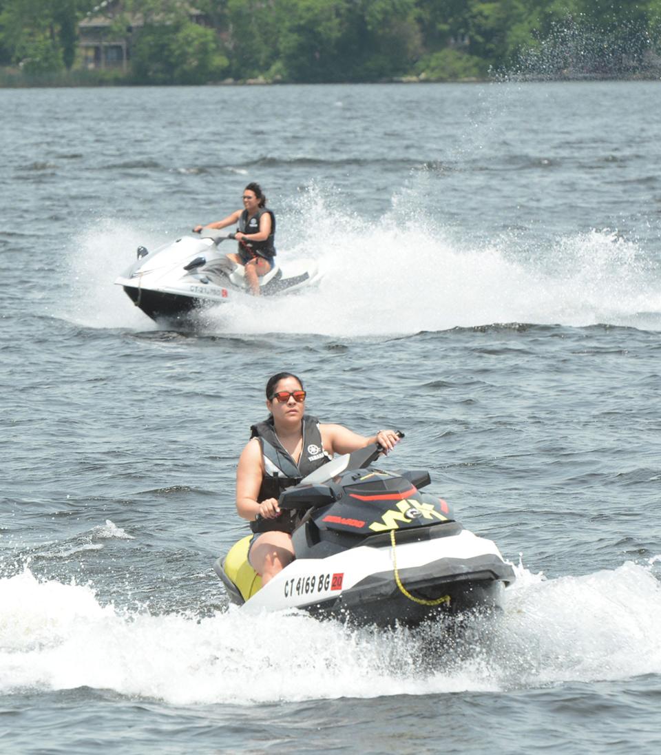 Barbara Hernandez of North Stonington, front, and her daughter, Jarelis Bentes of New London stay cool on their jet skis Tuesday at Gardner Lake in Salem. Admission is free for in-state residents.