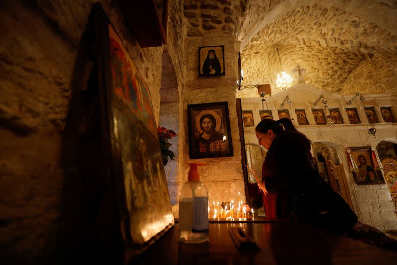 Christian woman lights candles inside St. George Church, also known as the Church of the Ten Lepers, in Burqin