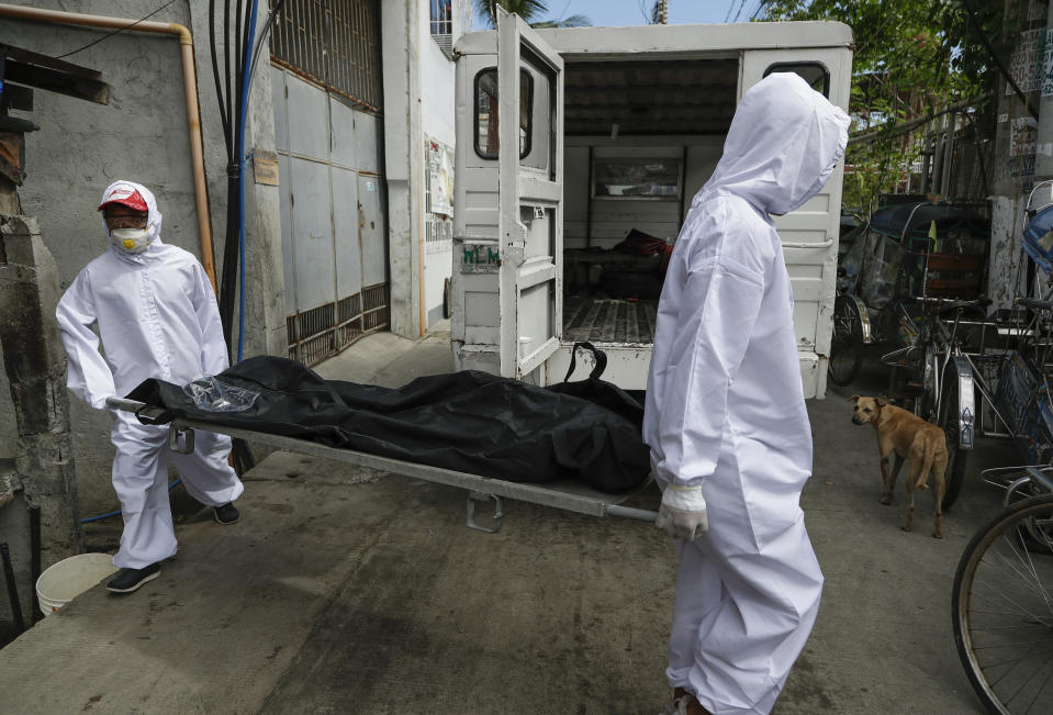 Trabajadores de una funeraria, vestidos con trajes de protección, trasladan un cadáver al inicio de una cuarentena por el repunte de los casos de coronavirus, en la ciudad de Navotas, Manila, Filipinas, el 16 de julio de 2020. (AP Foto/Aaron Favila)
