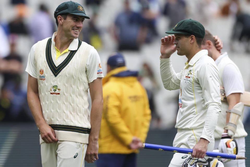 Australia's Pat Cummins, left, speaks to Alex Carey, right, as he leads the Australian team off the field after they defeated South Africa by and innings and 182 runs during the second cricket test between South Africa and Australia at the Melbourne Cricket Ground, Australia, Thursday, Dec. 29, 2022. (AP Photo/Asanka Brendon Ratnayake)