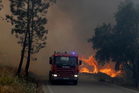 A fire engine drives through smoke from a forest fire in Chaveira