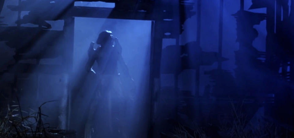 A shadowy figure stands in a doorway with a blue-lit, eerie atmosphere and surrounding silhouettes of what appears to be a dilapidated building