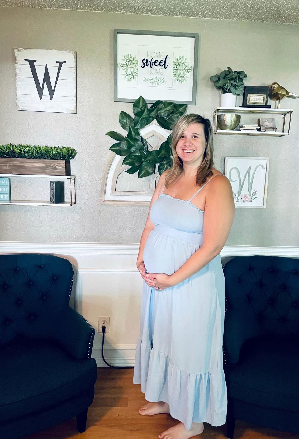 Cara Winhold poses in a blue sundress at her home when she is 26 weeks' pregnant with two boys conceived a week apart.