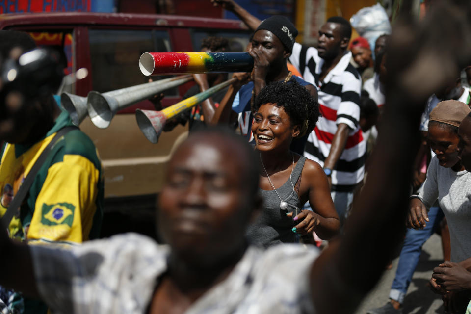 People dance as they march along with a band in Petion-Ville, Port-au-Prince, Haiti, Monday, Oct. 21, 2019. Anger over corruption, inflation and scarcity of basic goods including fuel has led to large demonstrations that began more than a month ago and have shuttered many businesses and schools. (AP Photo/Rebecca Blackwell)