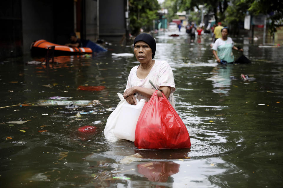 A woman wades flood water in Jakarta, Indonesia, Saturday, Jan. 4, 2020. Monsoon rains and rising rivers submerged parts of greater Jakarta and caused landslides in neighboring regions which buried a number of people. (AP Photo/Dita Alangkara)