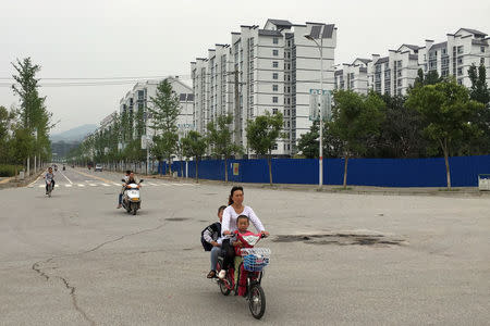 People ride electric scooters down a street in a resettlement town in rural Shaanxi province, China, June 12, 2017. REUTERS/Sue-Lin Wong