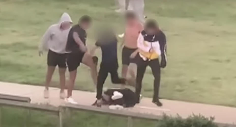 Five young men gang up on a single victim, kicking him in his head and body.