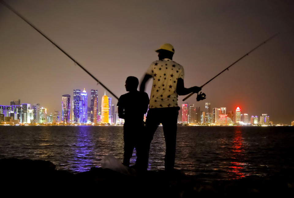 In this Friday, Nov. 2, 2018 photo, people fish in front of the Doha, Qatar skyline. Logistically, Qatar pulled off the 2018 world gymnastics championships largely without a hitch, yet the majority of the 10-day event was played in front of sparse crowds at the Aspire Dome. (AP Photo/Vadim Ghirda)